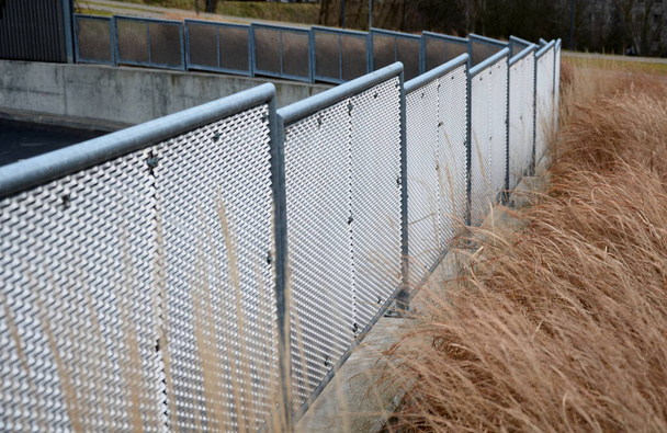 perforated expanded metal sheet metal fencing. Very durable railing made of galvanized railing frame. The strip of ornamental grasses gives the space an infustrial look. semi-transparent as a grater - Photo, Image
