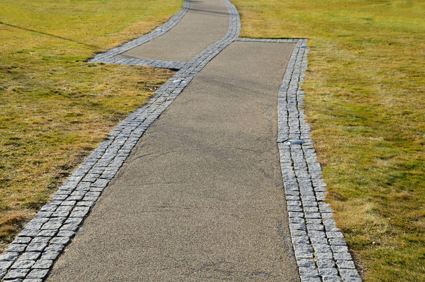 Dwie ścieżki w parku idą obok siebie łączą tylko krawędzie. Wygląda na to, że firmy budowlane nie uderzyły i nie zbudowały dróg, żeby się nie spotkały. błąd projektu lub zachcianka projektu - Zdjęcie, obraz