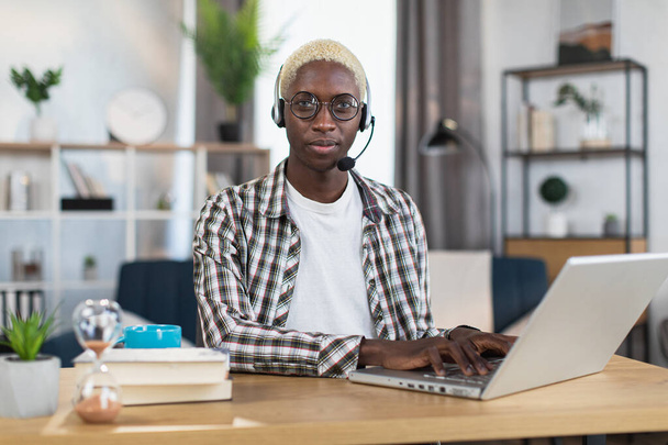 African american man in headset typing on laptop at home - Foto, Imagem