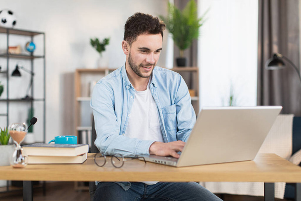 Man sitting at home and typing on wireless laptop - Valokuva, kuva
