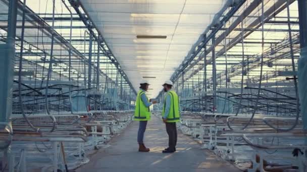Dispositivo de dos trabajadores de fábrica que muestra nuevos ingenieros de datos de seguridad discutiendo  - Imágenes, Vídeo