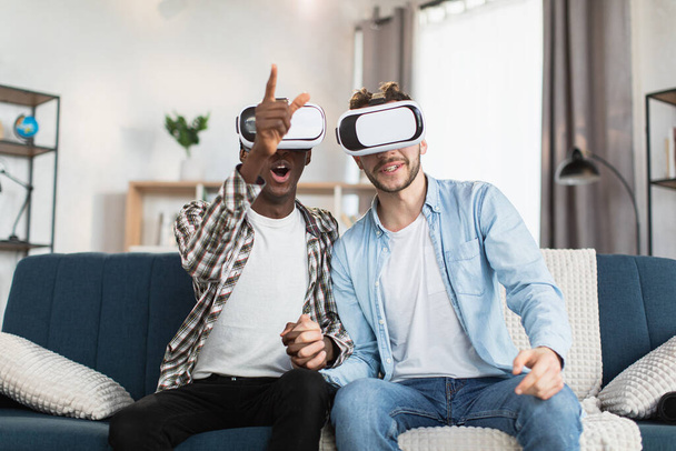 Same sex couple using VR goggles during free time at home - Fotó, kép