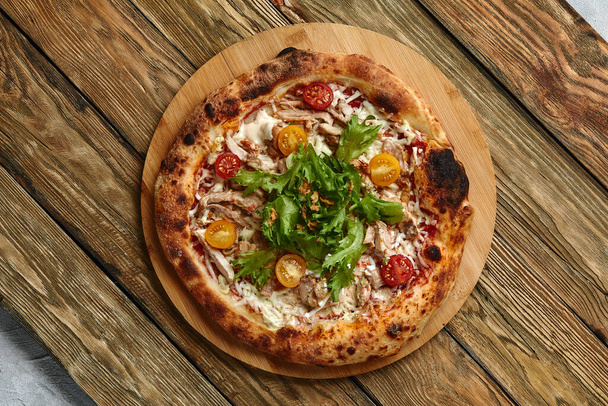 Pizzaa, Caesar. Pizza kanaa, tomaattia, juustoa ja salaattia puulaudalla. Huippunäkymä. Vapaa tila tekstillesi. Elintarvikkeiden toimitus - Valokuva, kuva