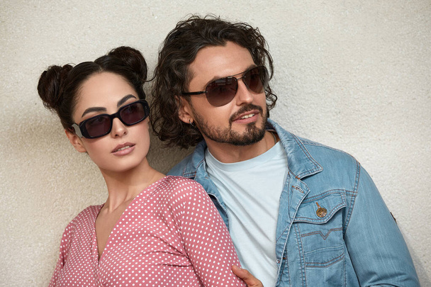 Fashion models couple wearing sunglasses. Sexy woman and handsome young man portrait over lite background. Attractive fashion Boy and girl posing. Hairstyle, haircut - 写真・画像