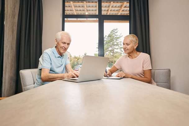 Два зрелых человека сидят за столом - Фото, изображение