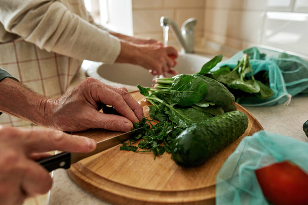 Image recadrée de la salade de cuisine du couple senior - Photo, image