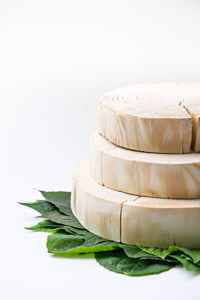 függőleges három kerek fa dobogók, dugványok zöld leveleken öko-organikus kozmetikai termékek bemutatásához - Fotó, kép