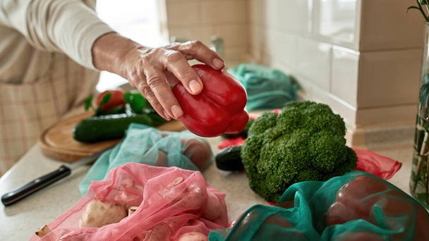 Senior woman taking red pepper while cooking salad - Fotografie, Obrázek