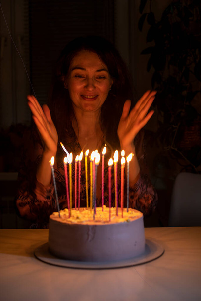 happy girl claps her hands before blowing out the candles on her birthday cake, vertica - Photo, Image