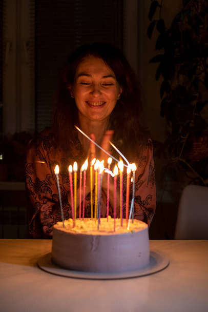 feliz chica sopla las velas en el pastel en su cumpleaños, vertical - Foto, Imagen