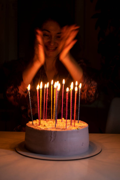 happy girl claps her hands before blowing out the candles on her birthday cake - Photo, image