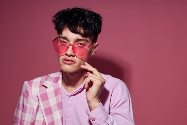 A young man in pink glasses pink blazer posing studio pink background unaltered - Foto, Imagem