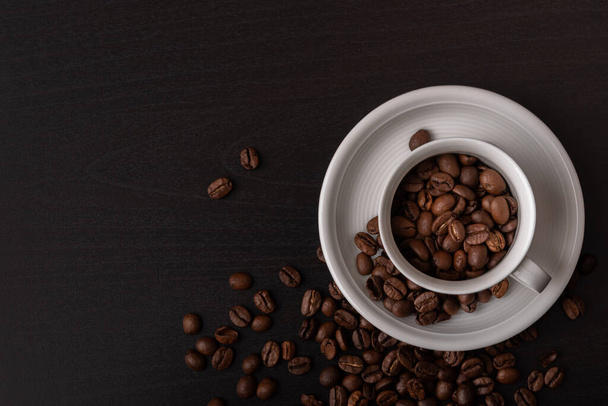 Hnědá pražená kávová zrna rozptýlená na černém pozadí - Fotografie, Obrázek