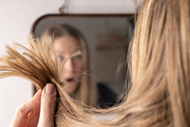 mladá žena před zrcadlem smutný rozrušený s vypadávání vlasů problém poškození - Fotografie, Obrázek