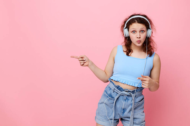 cheerful girl wearing headphones posing music pink background entertainment unaltered - Valokuva, kuva