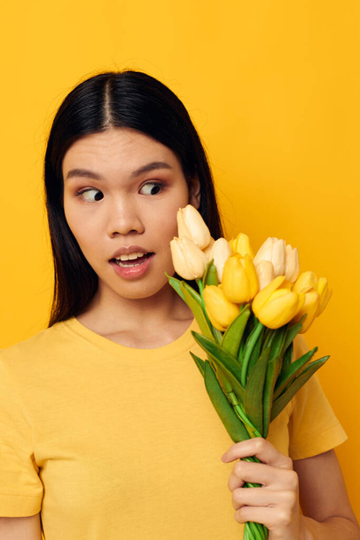 woman in a yellow t-shirt t-shirt with a bouquet of flowers holiday Lifestyle unaltered - 写真・画像