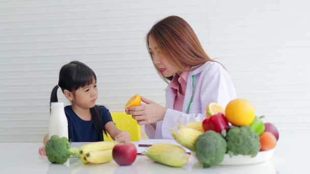 bella asiatica nutrizionista Spiegare i benefici del cibo ad una bambina carina. Il concetto di scegliere cibi che sono benefici per la crescita dei bambini. - Filmati, video