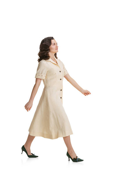 Young beautiful girl in retro style dress, fashion of 70s, 80s years walking isolated on white studio background with copyspace for ad. - Foto, Bild