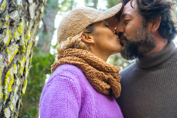 Miłość i związek dorosła para mężczyzna i kobieta całujący się na świeżym powietrzu. Ludzie razem w romantycznej scenie z lasu na zewnątrz parku w tle. Romantyczna rozrywka ludzie - Zdjęcie, obraz