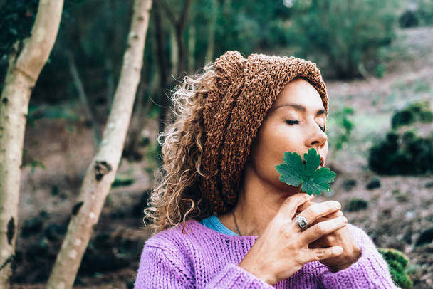Красивая женщина любитель природы и внутренняя жизнь баланс медитации образ жизни. Мечтающие женщины держат зеленый лист в лесу с лесом на заднем плане. Чувство человека и земли - Фото, изображение