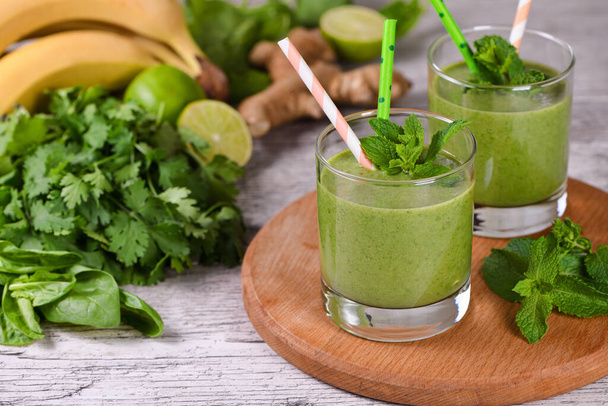 Świeże ekologiczne detox zielony drink smoothie z selerem, szpinakiem, bananem, kolendrą, limonką i imbirem z orzeźwiającą miętą. Zdrowe, dietetyczne, wegetariańskie jedzenie - Zdjęcie, obraz