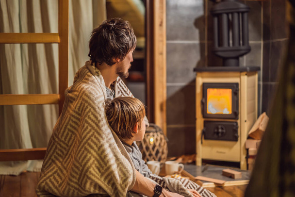 Dad and son spend time by the fireplace in Glamping. Rest in the mountains in Glamping. Cozy fireplace in a mountain house - 写真・画像