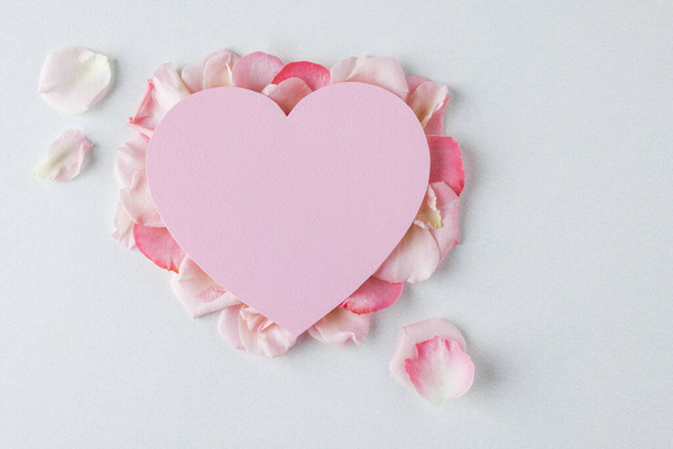 Valentine's Day background. Creative layout with pink flowers, paper heart over punchy pastel background. Top view, flat lay. Spring, summer or garden concept. Present for Woman day.  - Photo, Image