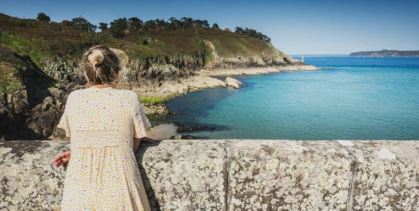 Woman leaning on embankment overlooking sea, Brittany, France - Fotoğraf, Görsel