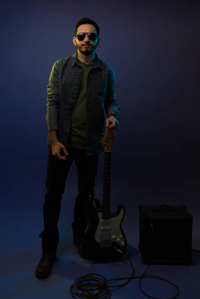 Músico de rock and roll. Cantor atraente com uma guitarra elétrica preta e amplificador pronto para um concerto divertido - Foto, Imagem