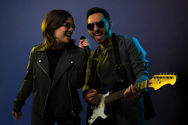Leuk rockconcert. Aantrekkelijke Kaukasische zangeres die met een mannelijke gitarist zingt tijdens een rock- 'n-roll concert - Foto, afbeelding