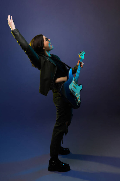 Χαρούμενη ροκ εν ρολ γυναίκα μουσικός ουρλιάζοντας στο κοινό, ενώ παίζει την ηλεκτρική κιθάρα  - Φωτογραφία, εικόνα