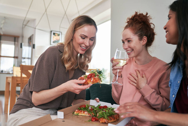 Blanke vrouwelijke vrienden eten pizza thuis en hebben plezier - Foto, afbeelding