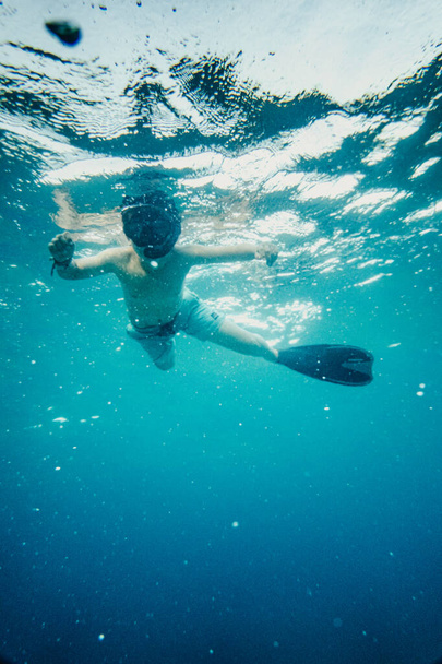 Αγόρι με μάσκα κατάδυσης και πτερύγια που κολυμπάνε κάτω από το νερό - Φωτογραφία, εικόνα