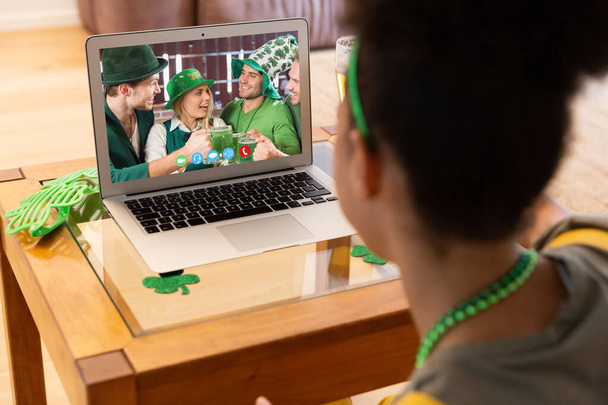 African american woman having a video call on laptop at home. st patricks celebration concept - Foto, immagini