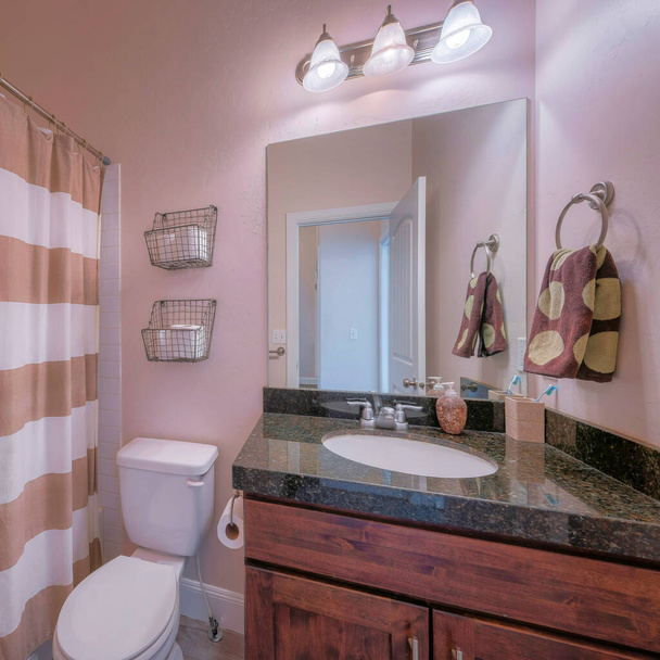 Plaza Pequeño cuarto de baño interior con lavabo tocador de madera oscura y encimera de granito negro - Foto, imagen