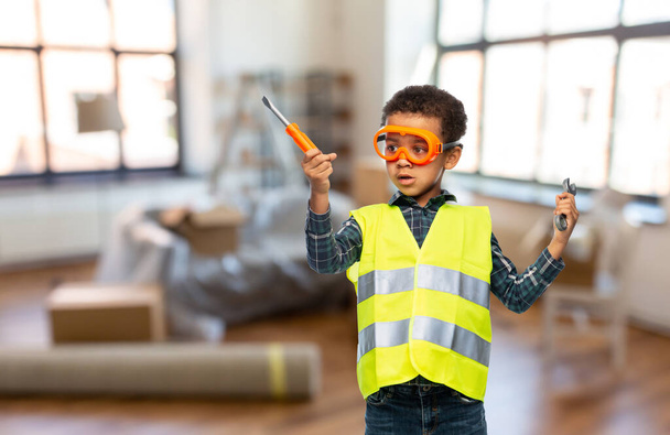 little boy in safety vest with screwdriver at home - Fotó, kép