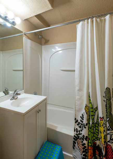 Vertikale Innenausstattung eines Badezimmers mit weißem Duschvorhang mit bedrucktem Kakteen-Design - Foto, Bild