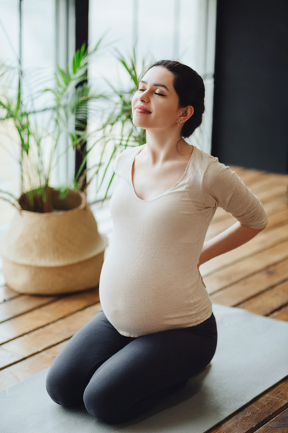 Hamilelik sırasında meditasyon. Genç, sakin, hamile bir kadın evde yoga yapıyor, meditasyon yapıyor ve farkındalık yapıyor, anne adayı Lotus 'ta gözleri kapalı oturuyor.  - Fotoğraf, Görsel