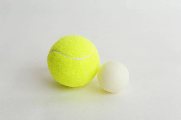 Großer Tennisball und kleiner weißer Tischtennisball auf weißem Hintergrund. Sportkonzept - Foto, Bild