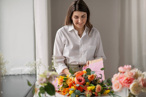 woman wrapping flowers to craft paper at home - Foto, immagini