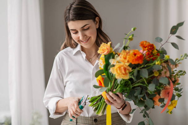 happy woman making bunch of flowers at home - Zdjęcie, obraz