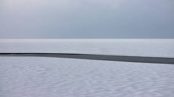曇りの日に美しい巨大な湖。水面に亀裂がある湖の表面。冬の期間。高品質の写真 - 写真・画像