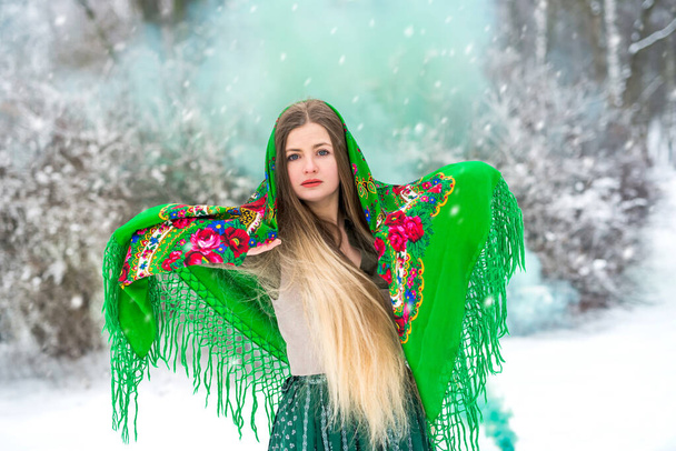 Piękna kobieta w zimowym lesie z zieloną bombą dymną. - Zdjęcie, obraz