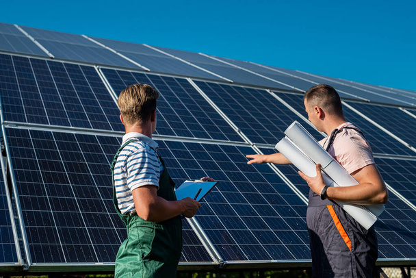 Δύο επαγγελματίες εργολάβοι συζητούν το τελικό αποτέλεσμα της εγκατάστασης ηλιακών πάνελ - Φωτογραφία, εικόνα