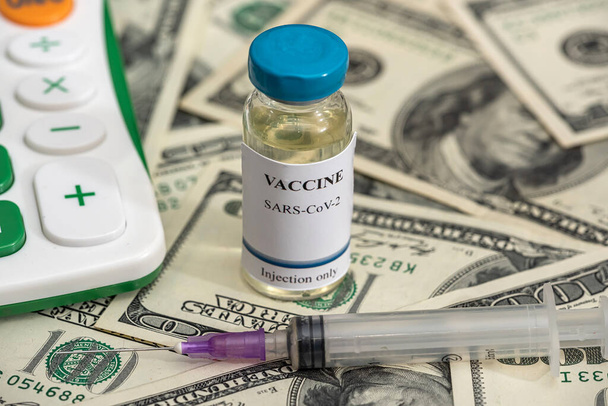 Aşı şişeleri bir salgın sırasında büyük miktarlarda banknotlarla dolu bir hesap makinesiyle. Standardın altında aşı kavramı. Yozlaşma - Fotoğraf, Görsel