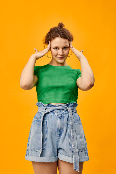 cute girl in a green t-shirt gestures with hands emotions yellow background - Foto, afbeelding