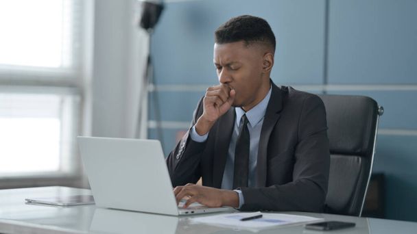 Afrikaanse zakenman hoesten tijdens het gebruik van Laptop in Office - Foto, afbeelding
