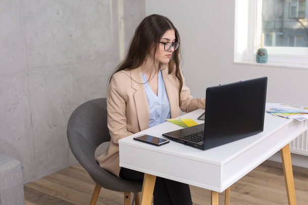 Una giovane designer seduta a un tavolo attinge da una tavoletta. Fa calcoli di affari sul computer. - Foto, immagini