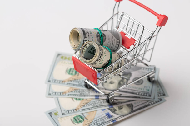 American banknotes in a metal grocery basket on a white background. - Фото, изображение