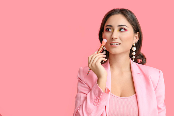 Vrouw met creatieve make-up houden borstel op roze achtergrond. Internationale Vrouwendag - Foto, afbeelding